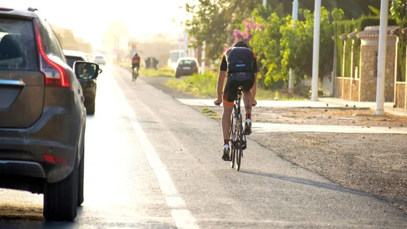 Turismo adelantando a un ciclista en una carretera, desplazado al carril contrario y dejando la separación lateral de al menos metro y medio