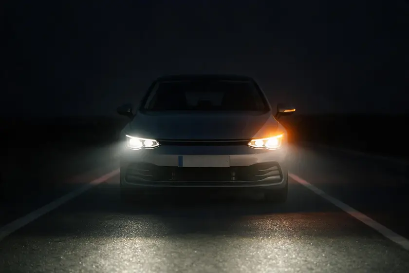 Coche de noche visto de frente con la luz de cruce encendida y el intermitente izquierdo del vehículo en ámbar