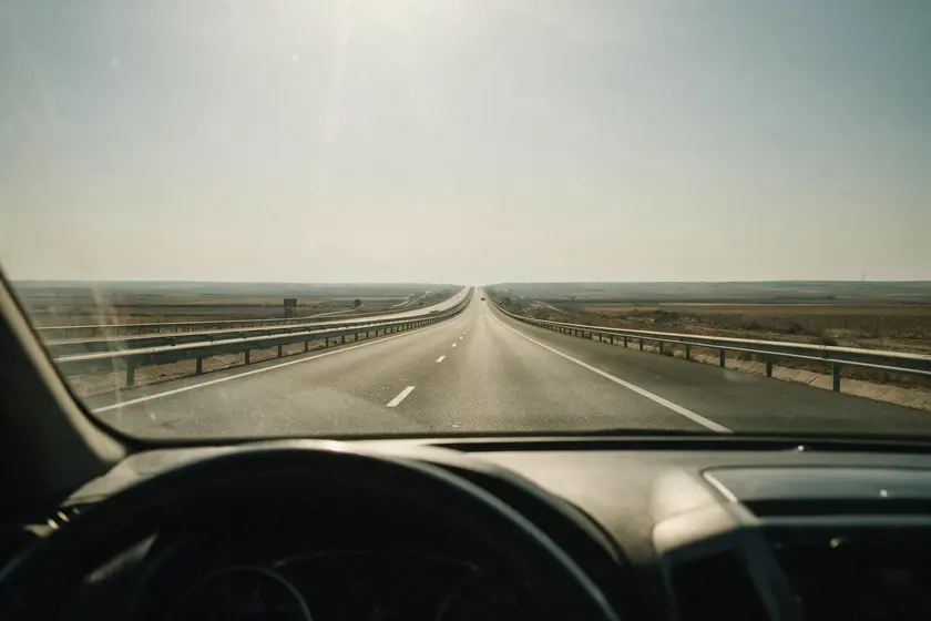 Autovía completamente recta y vacía que se pierde en el horizonte, vista desde el puesto del conductor