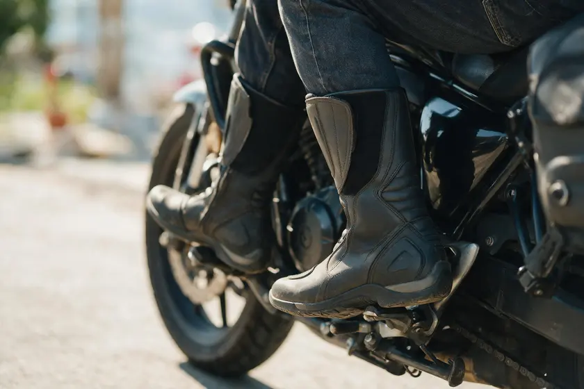 Botas de motorista altas y con tacón, ajustadas, sobre los reposapiés