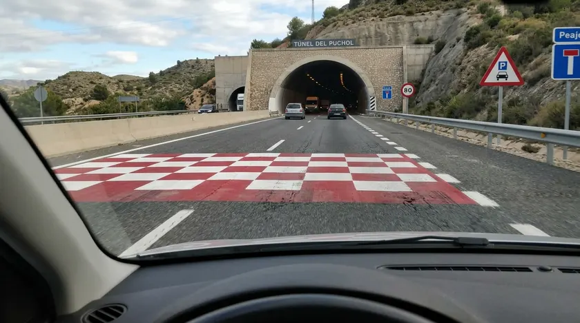 Cuadrícula de marcas blancas y rojas sobre la calzada cerca de un túnel