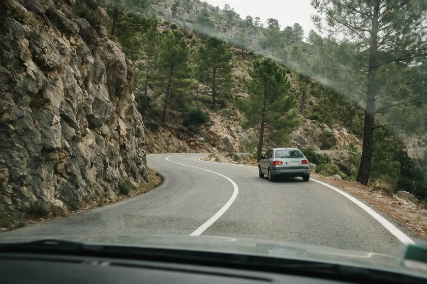 Curva de montaña sin visibilidad, con el vehículo circulando pegado a su derecha