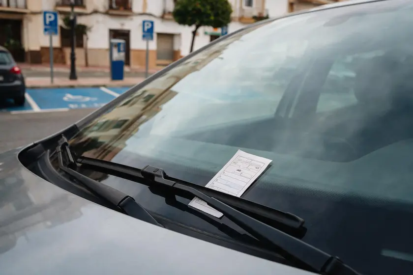 Tique de estacionamiento de zona azul colocado sobre el salpicadero y visible desde la calle