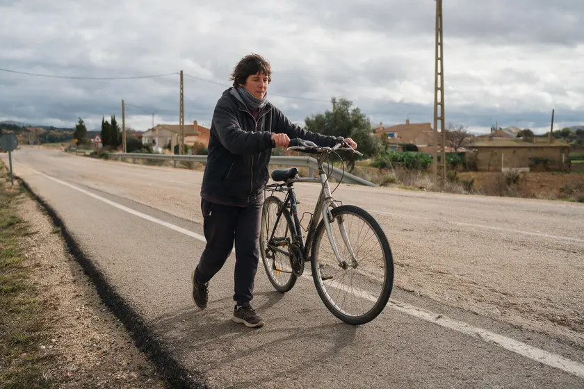 Persona empujando su bicicleta caminando por el arcén