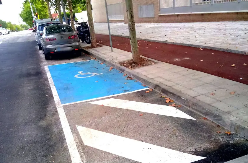 Plaza de estacionamiento reservada, pintada en azul con el símbolo de silla de ruedas