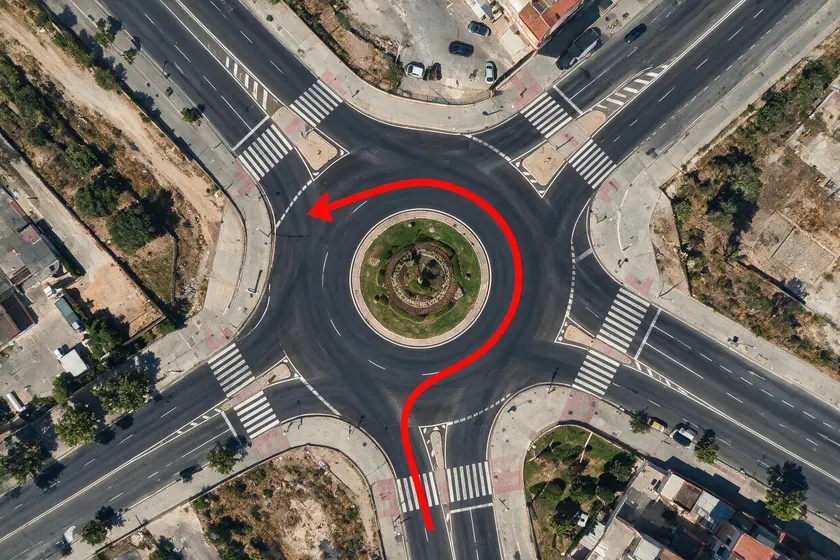 Coche girando a la izquierda en un cruce dejando el centro de la intersección a su izquierda