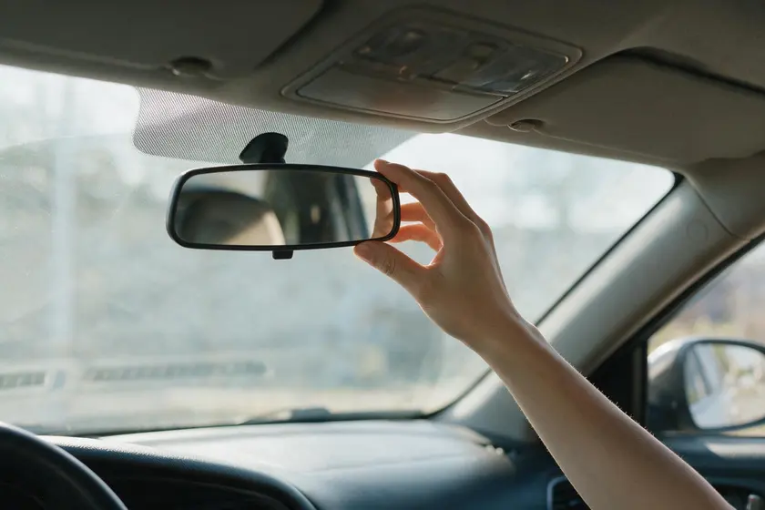 Mano regulando el espejo retrovisor interior cogiéndolo por los bordes