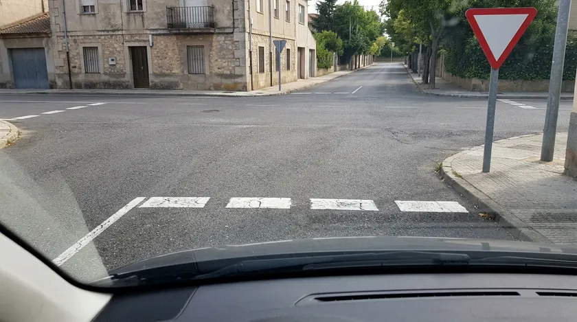 Línea blanca discontinua a lo ancho del carril junto a una señal de ceda el paso