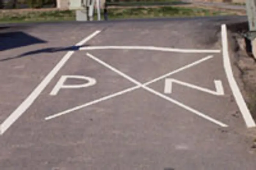 Marca vial con las letras P y N a cada lado de un aspa, indicando la proximidad de un paso a nivel