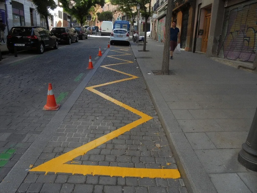 Línea amarilla en zigzag pintada junto al bordillo, indicando prohibición de parar