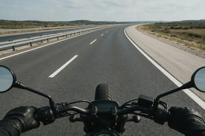 Autopista vista desde el manillar de una motocicleta, con barrera central a la izquierda y arcén a la derecha