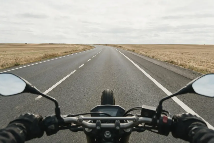 Carretera convencional vista desde el manillar de una motocicleta, con un carril por sentido y arcén