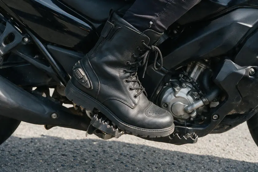 Bota de un motorista apoyada en el estribo o apoyapiés de la motocicleta