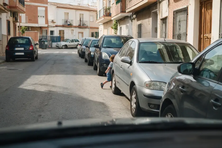 Niño saliendo a la calzada entre dos coches aparcados