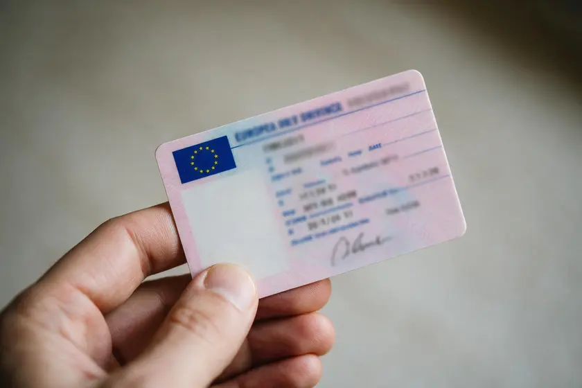 Mano sosteniendo un permiso de conducción europeo, sin datos legibles