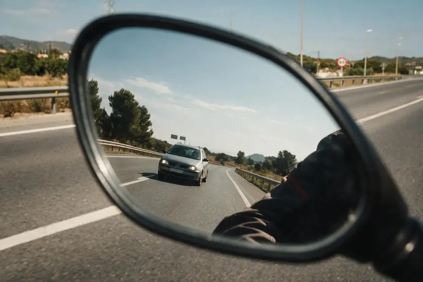 Retrovisor convexo de una motocicleta en el que el coche de detrás se ve más pequeño y lejano