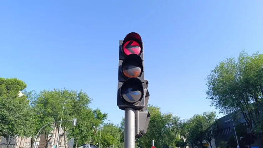 Semáforo real de flecha con la luz roja encendida mostrando una flecha negra apuntando a la izquierda