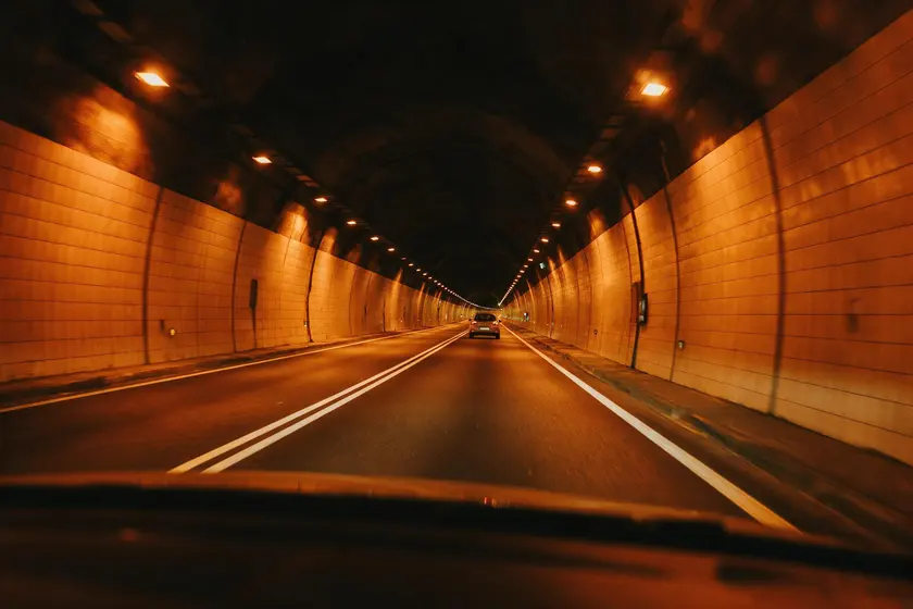 Interior de un túnel con un coche circulando muy por delante, dejando un gran espacio libre