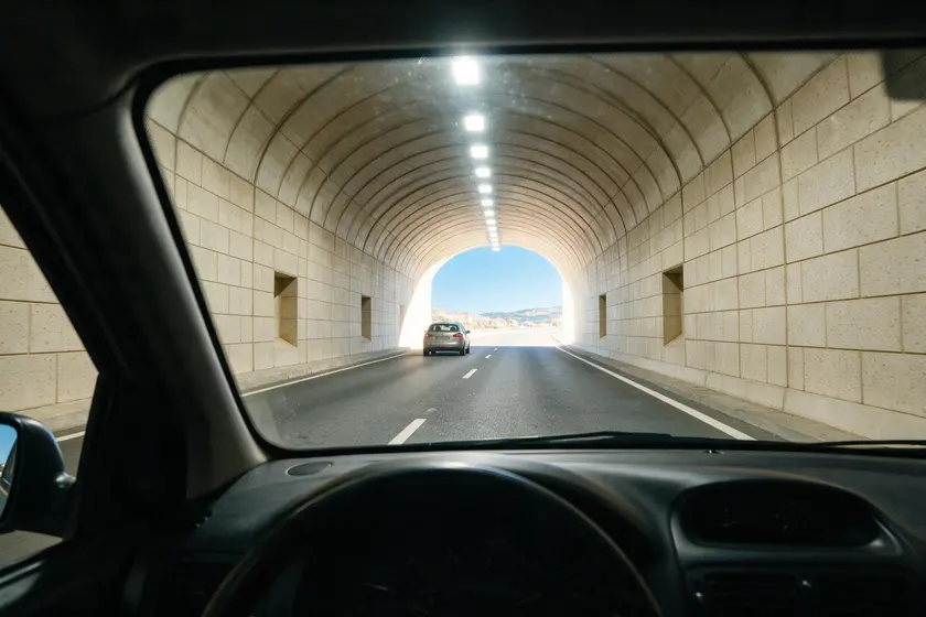 Interior de un túnel suficientemente iluminado, visto desde el puesto del conductor, con las luminarias del techo encendidas
