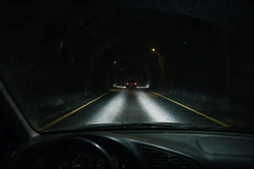 Interior de un túnel insuficientemente iluminado, visto desde el puesto del conductor, casi a oscuras