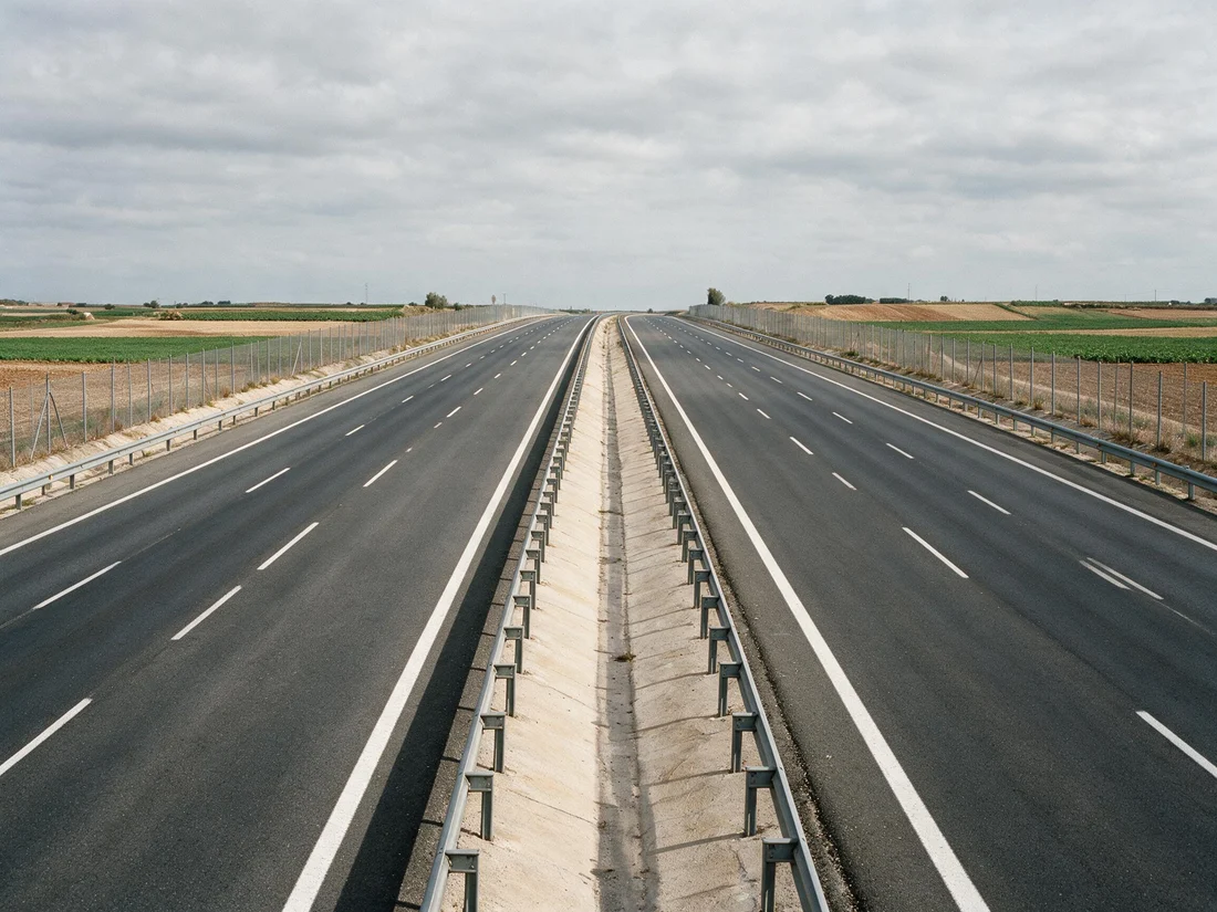 Autopista vista desde el puesto del conductor: calzadas separadas por una barrera metálica, varios carriles por sentido y arcén a la derecha