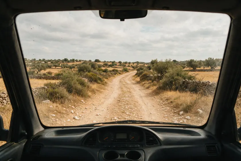 Camino sin pavimentar visto desde el puesto del conductor: tierra y grava, sin asfalto ni marcas viales