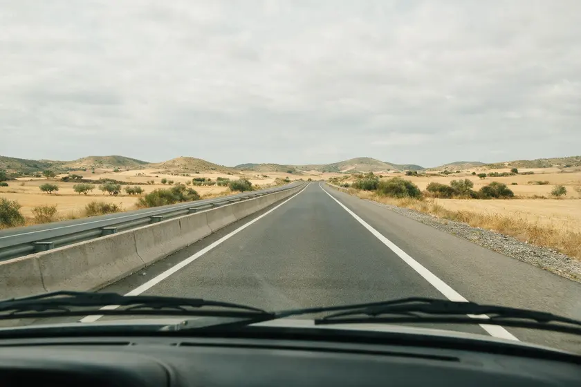 Carretera convencional vista desde el puesto del conductor, con los dos sentidos separados por una mediana de hormigón y barrera metálica