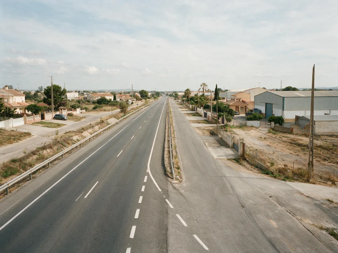 Vía de servicio paralela a una carretera principal, que da acceso a las fincas y edificios contiguos