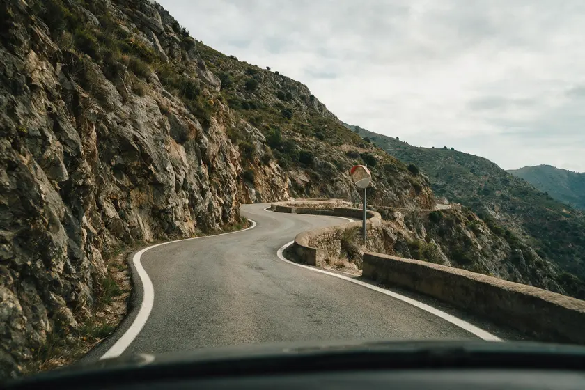 Carretera de montaña muy estrecha y con curvas cerradas sin visibilidad, con un espejo en la curva