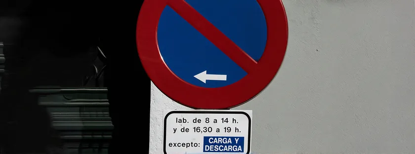 Señal circular azul de borde rojo con una franja diagonal y una flecha, y un panel debajo con horarios y una excepción escrita
