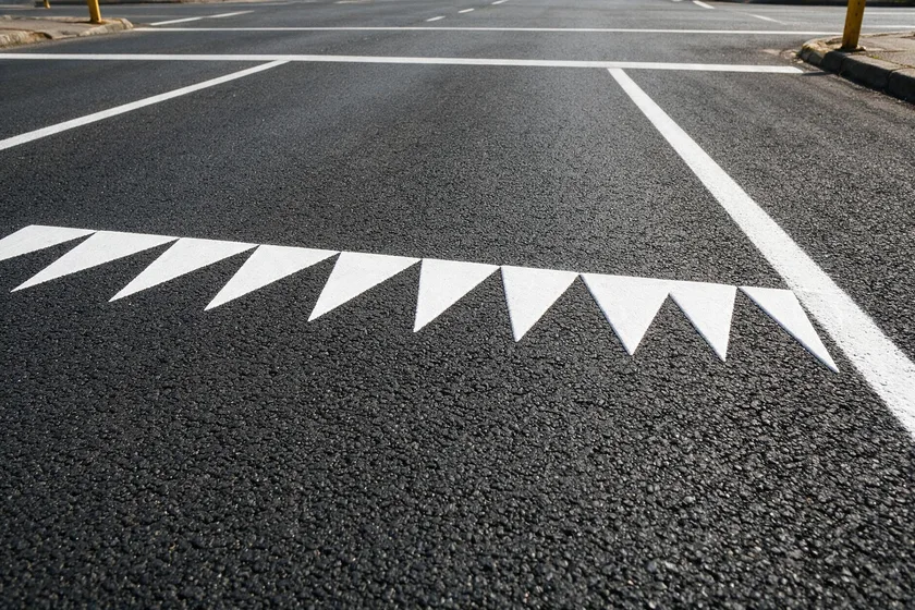 Fila de triángulos blancos pintados a lo ancho del carril, con las puntas hacia el conductor