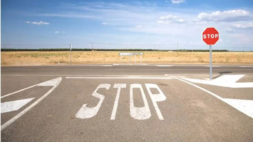 Palabra STOP pintada en blanco sobre el asfalto de un carril